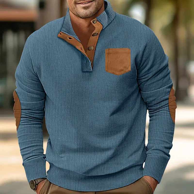Slim fit corduroy patchwork pullover in blue ribbed knit with brown leather collar, buttons, chest pocket, and elbow patches.