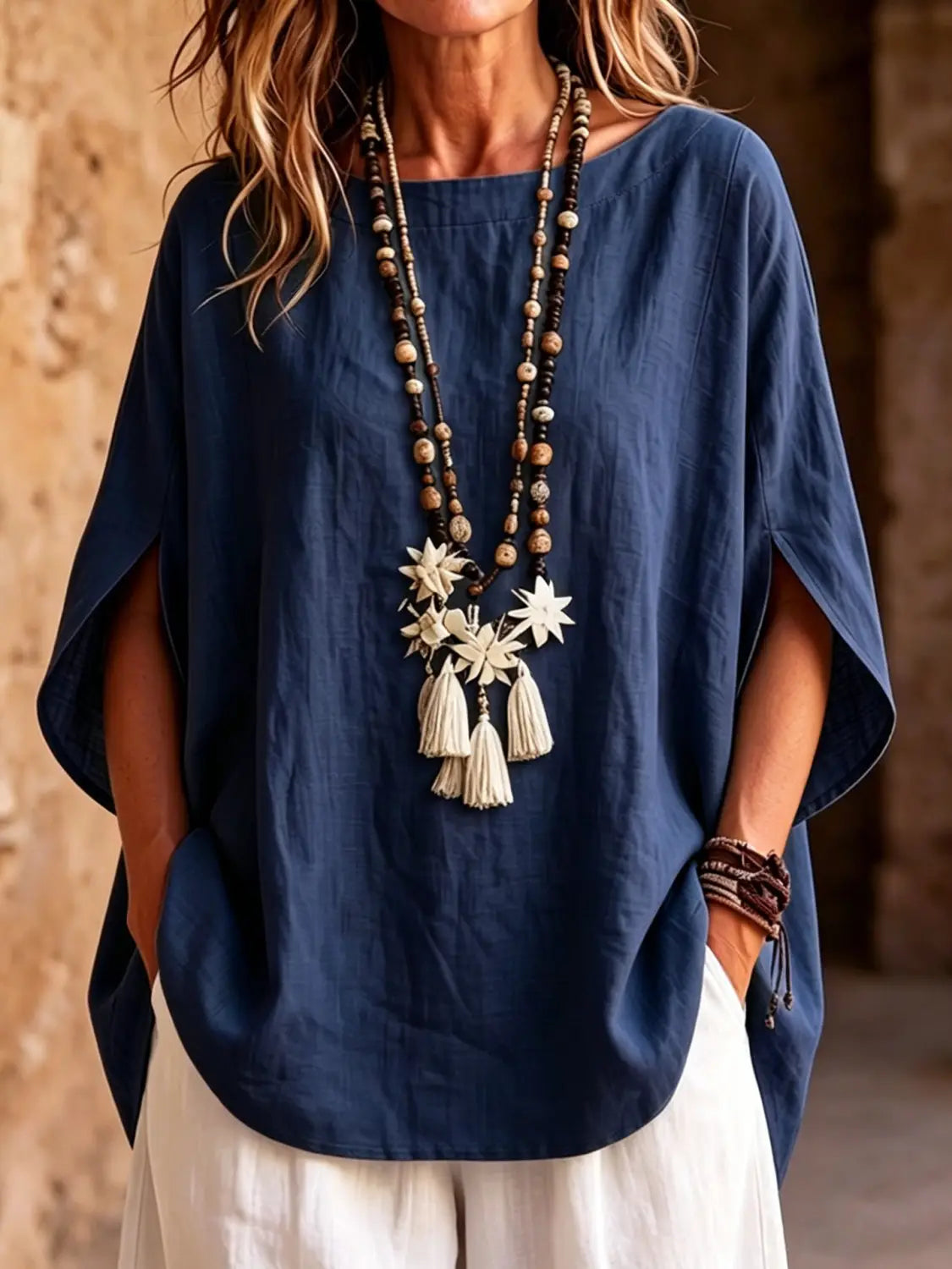 Una blusa tipo capa de lino azul marino con corte relajado y mangas murciélago anchas y de caída amplia.