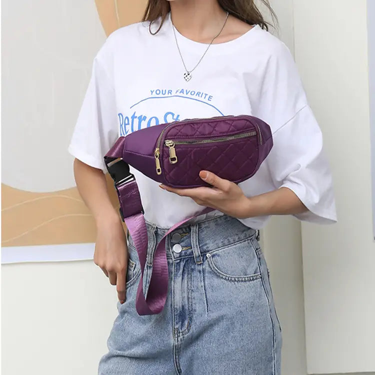 Lila gesteppte Crossbody-Gürteltasche für Damen und Sport mit goldfarbenen Reißverschlüssen und einem passenden verstellbaren Riemen.