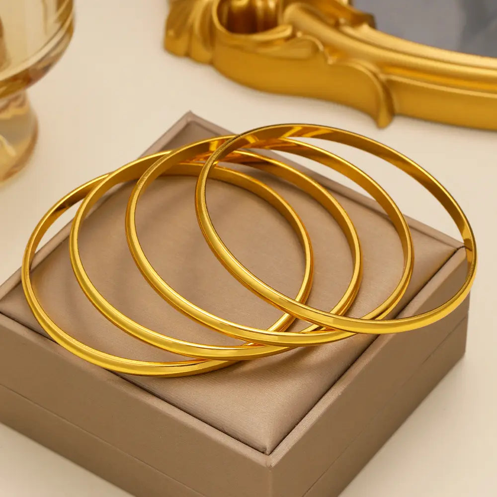 Set of four sleek solid gold bangles with a polished finish 18k gold plated minimalist stackable bangle set.