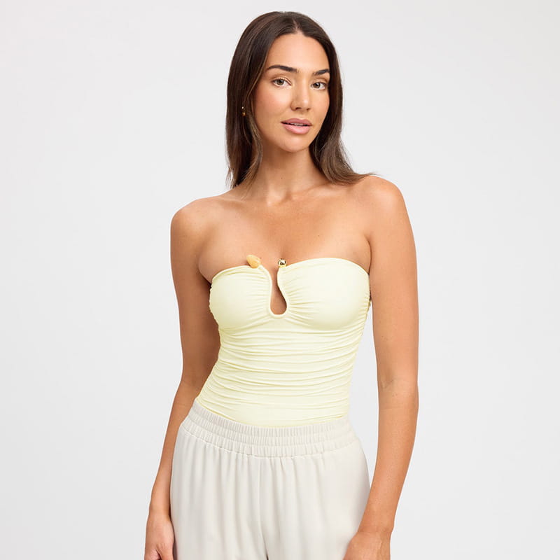 A pale yellow strapless keyhole crop top bodysuit with ruched texture and a central cutout at the bust.