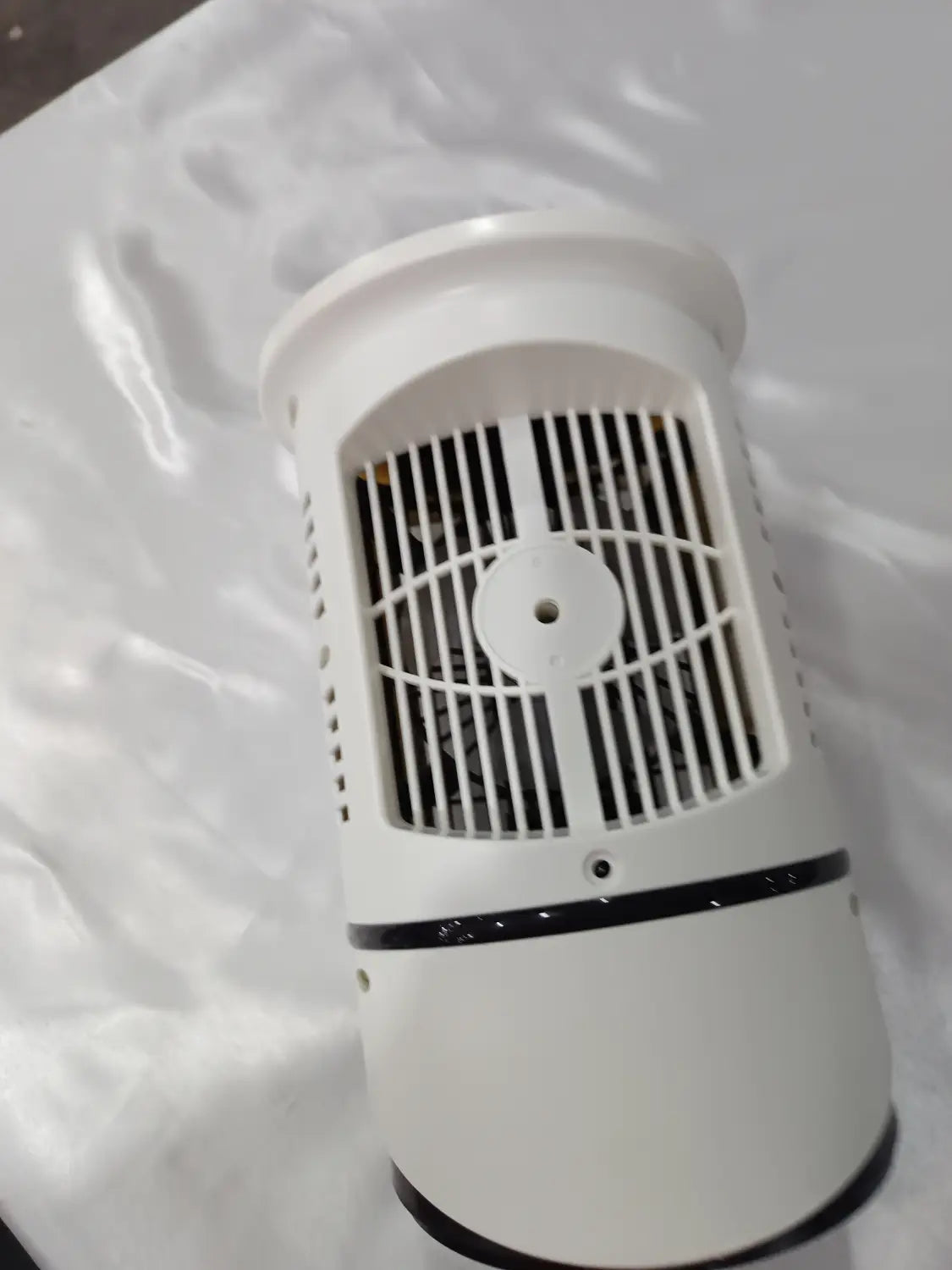 Ventilador cilíndrico portátil de enfriador de aire USB blanco con moldura de acento negra y carcasa del ventilador cubierta con una rejilla, mostrada desde el lado posterior.