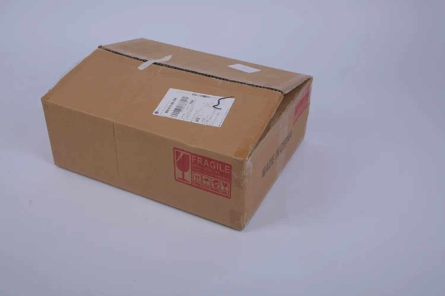 brown cardboard shipping box with red fragile label and white shipping sticker containing artificial boxwood ball topiary trees with spikes 2 pack