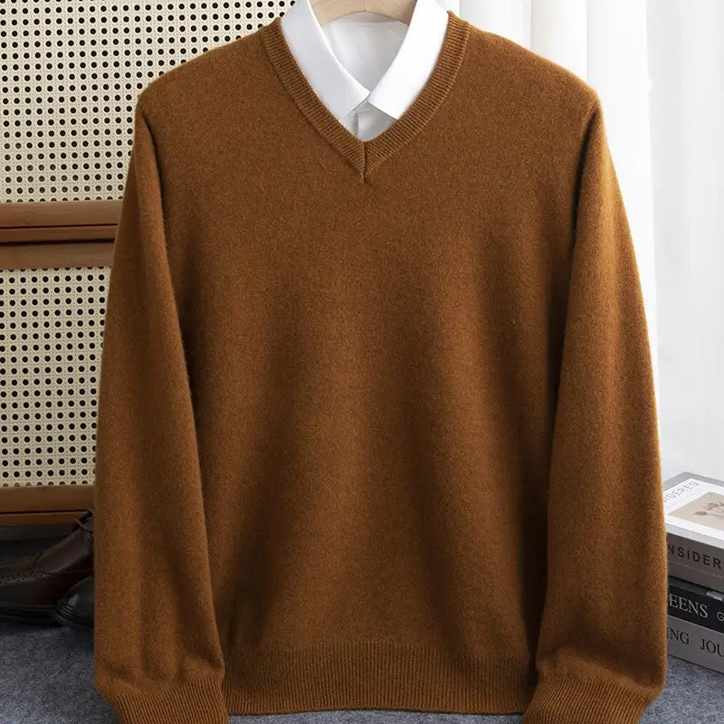 Ein warmer brauner Wollstrickpullover für Herren mit V-Ausschnitt und weichem Strickstoff, über einem weißen Hemdkragenhemd für den Winter präsentiert.