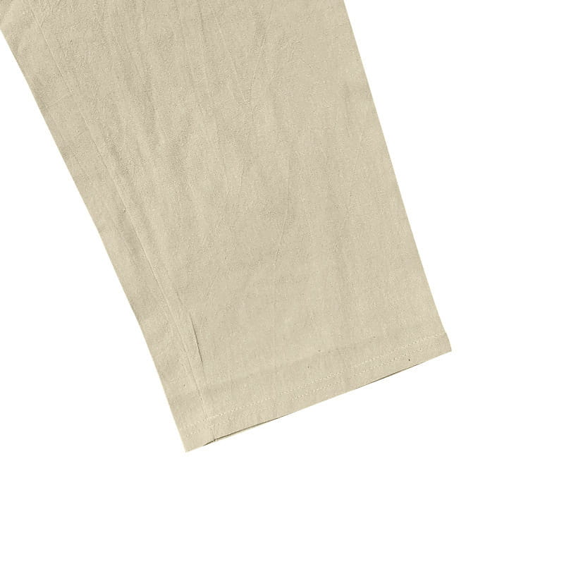 Beiges Baumwollmaterial mit subtiler Struktur und sauber verarbeitetem Saum aus dem Set mit Herren-Leinenhemd und -Hose.