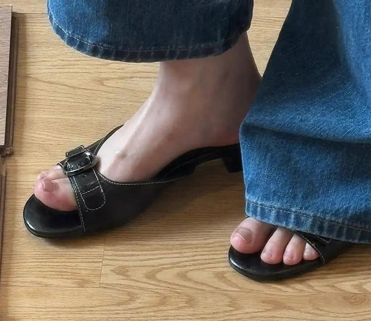 Sandalias tipo mule de cuero negro para mujer con puntera cuadrada, correa con hebilla y tacón bajo.