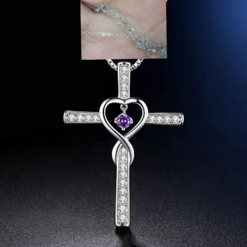 Silver cross pendant with a heart-shaped center featuring a purple birthstone and surrounded by clear crystals in the infinity love heart cross birthstone crystal necklace.
