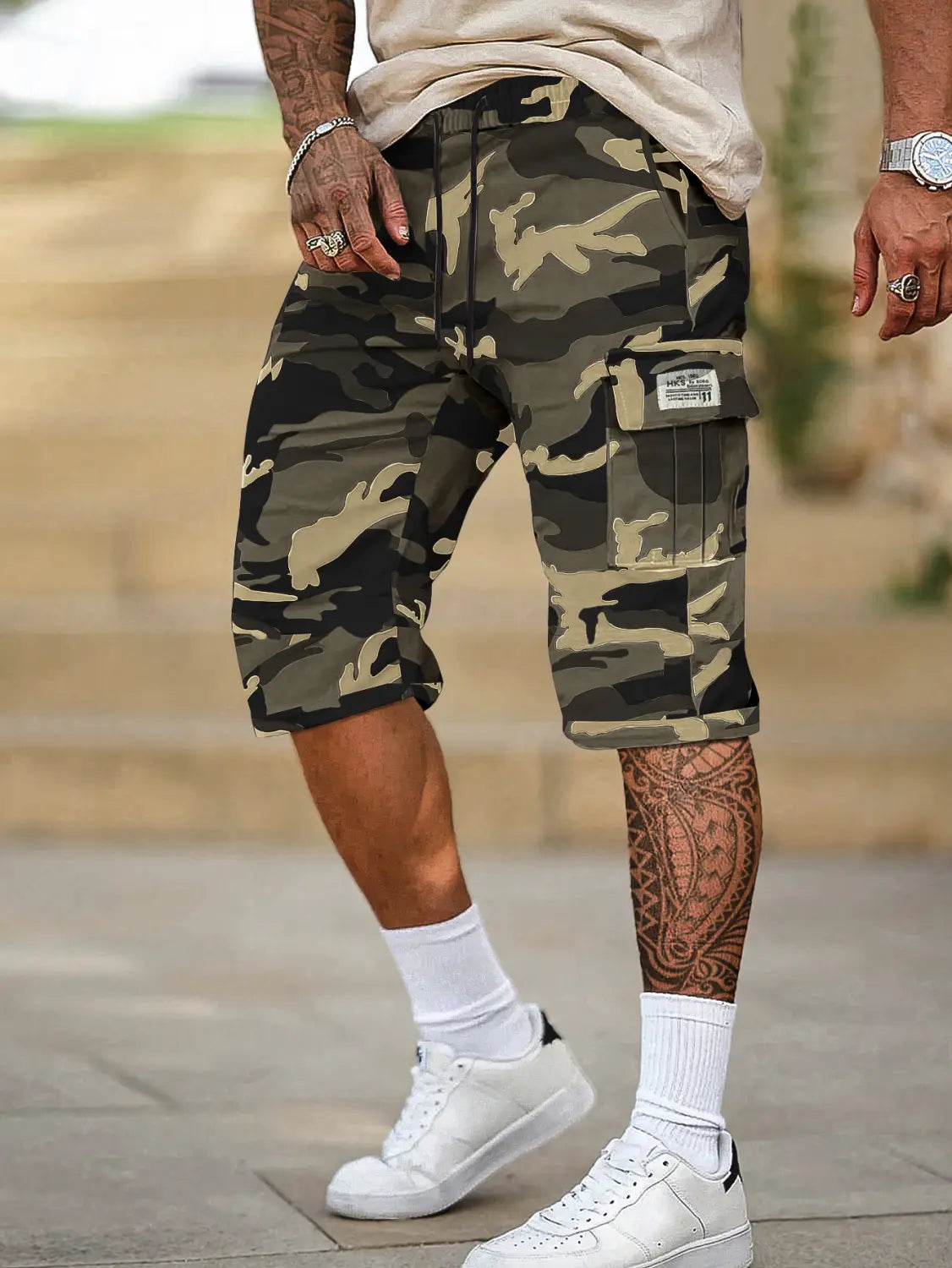 Short cargo camouflage pour homme, coupe ample, avec plusieurs poches, en tons olive, noir et camel, fabriqué à partir d’un tissu durable.
