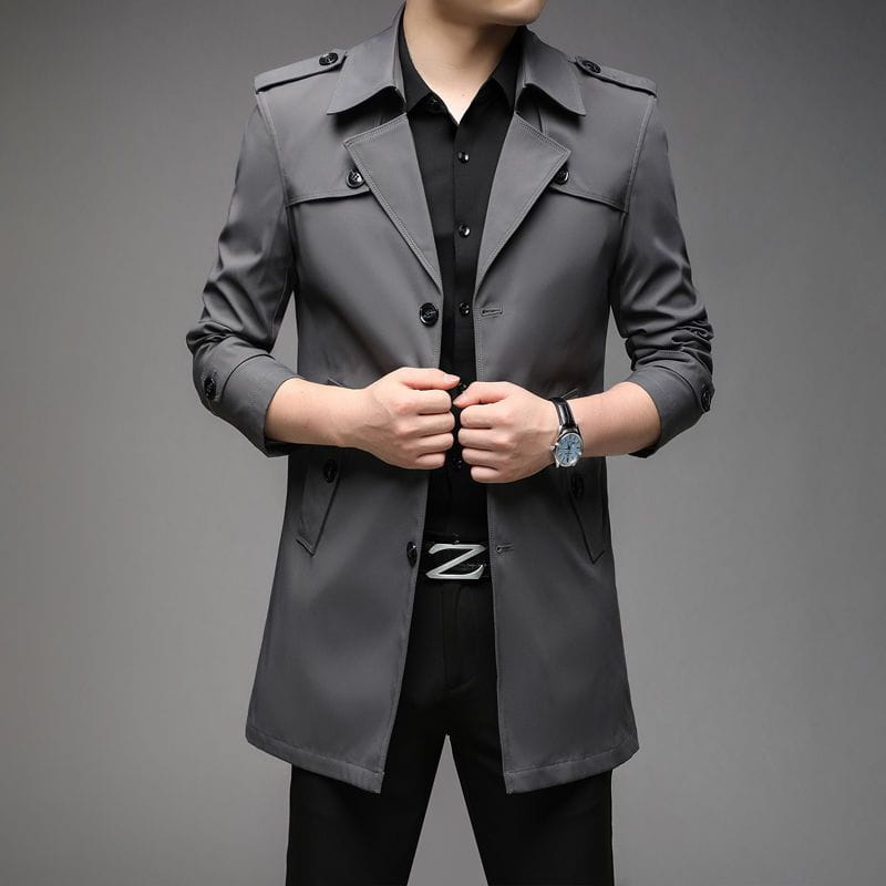 Un trench-coat d’affaires homme slim élégant en gris foncé, présentant un design classique à double boutonnage avec des boutons noirs.