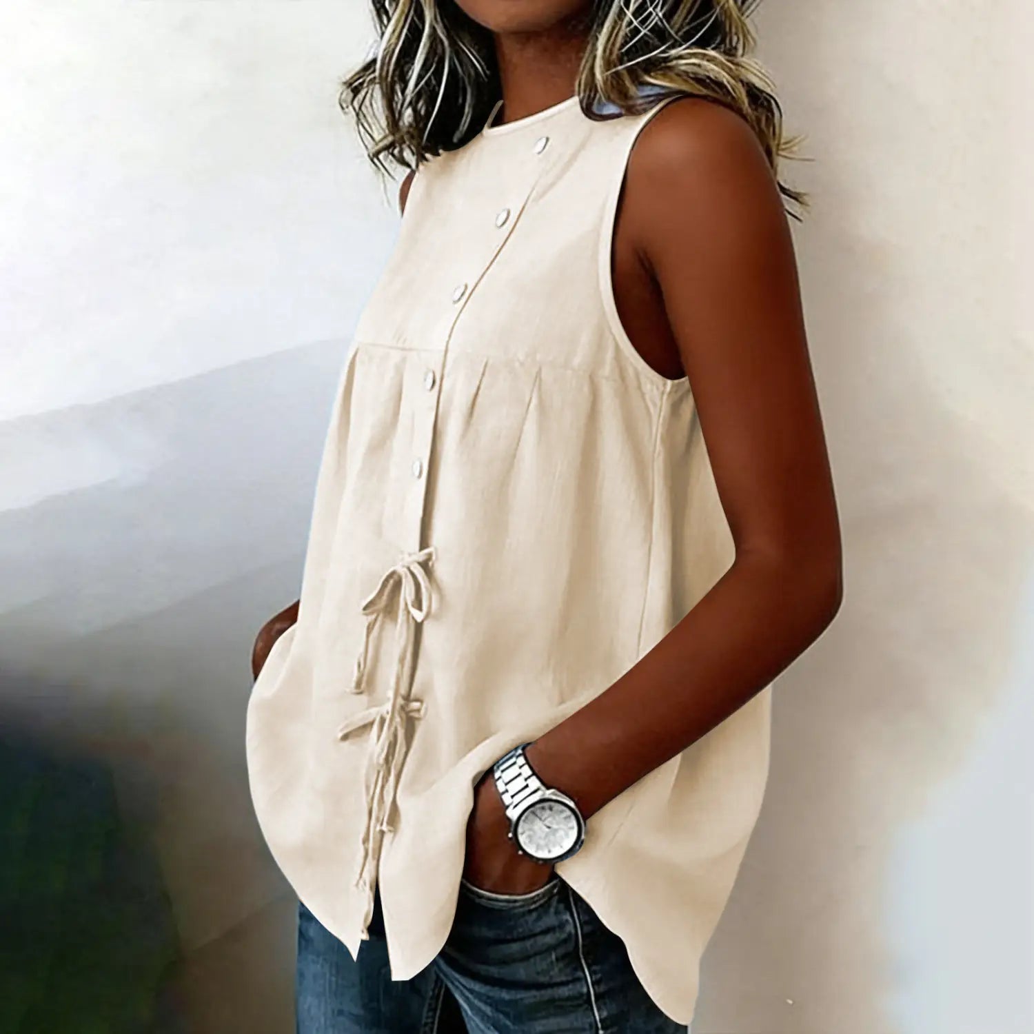 Beige sleeveless tie side button down blouse with button front closure and drawstring tie at the waist.