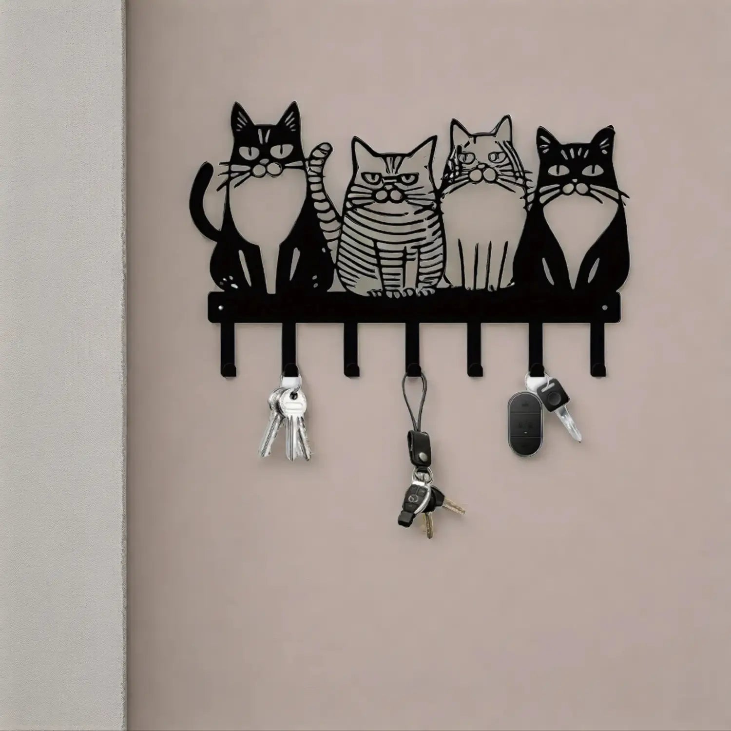 Black metal wall-mounted key holder featuring four stylized cat designs with distinct facial expressions and striped patterns for home decor.