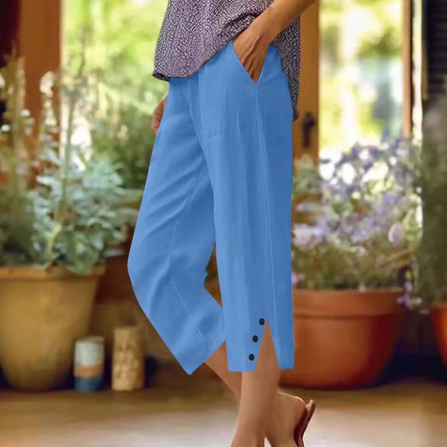 Pantalons capri amples en coton bleu clair pour femmes avec poches, présentant une coupe courte ample et des détails de boutons en bas.
