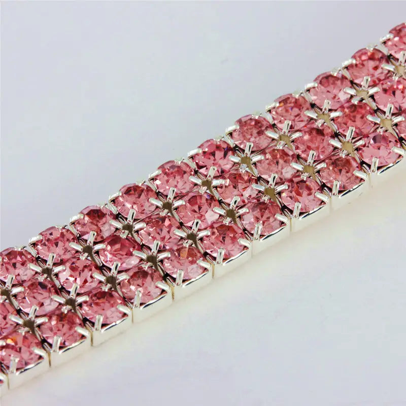 Un collier pour animal de compagnie en strass roses scintillant à motif de patte, conçu avec un modèle à double rangée, monté sur une base métallique à tons argentés.