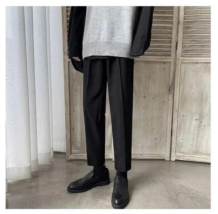 Men loose fit straight leg suit pants shown in black tapered trousers with a smooth matte finish and subtle creases.