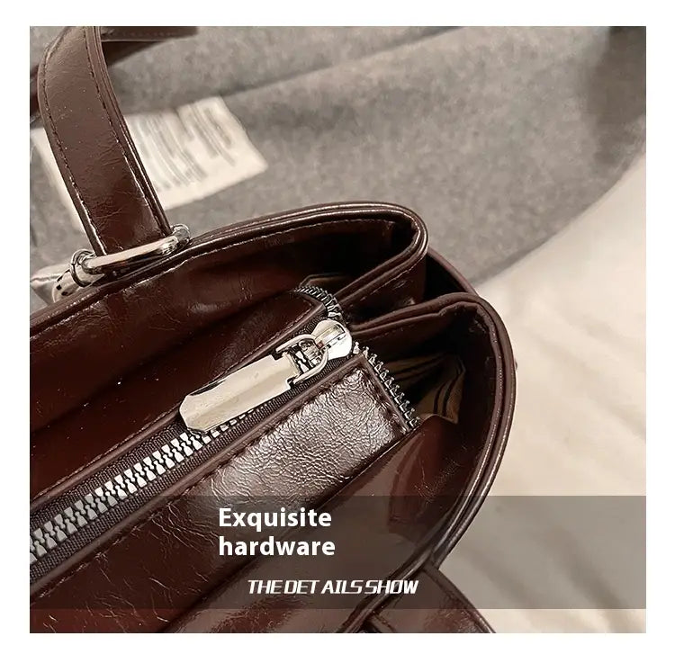Brown faux leather shoulder bag with buckle and bow charm featuring silver-toned zipper hardware.