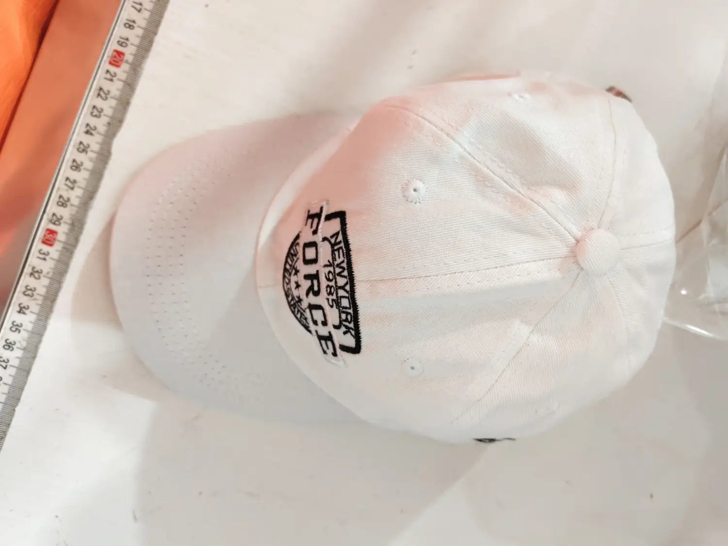 White baseball cap with black embroidered New York Force logo and small top button in New York Force embroidered baseball cap product.