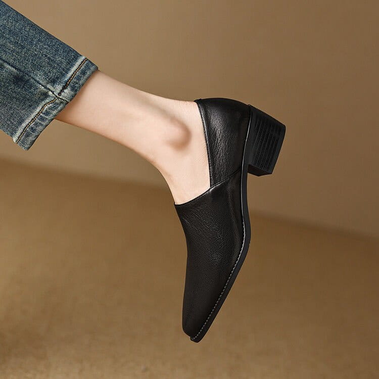Black leather slip-on womans loafer with low block heel and stitched detailing featuring a square toe design.