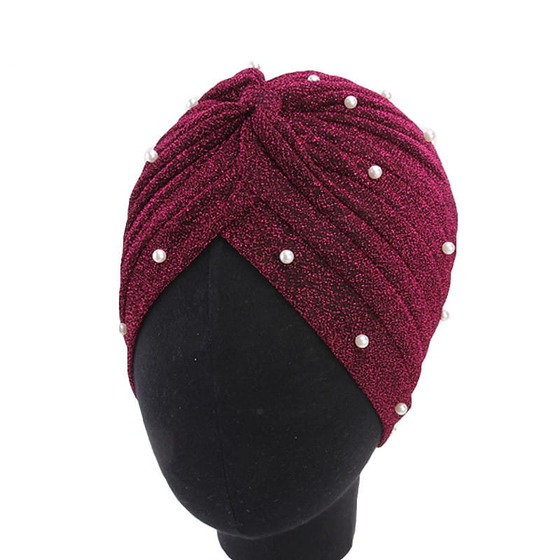 A shimmering burgundy jacquard pearl turban headscarf cap for women adorned with evenly spaced white pearls along its twisted textured surface.