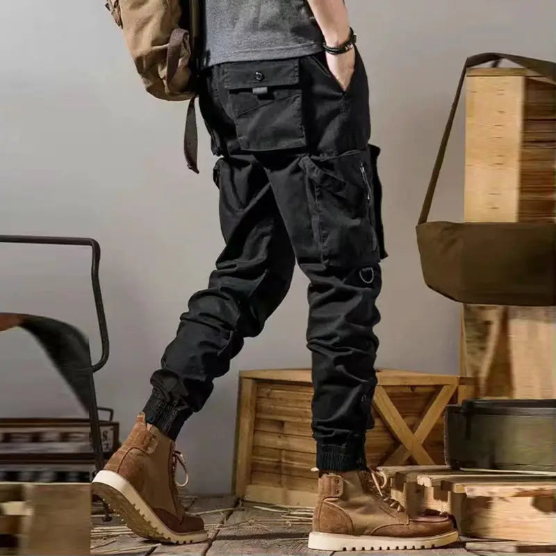 Black men tactical cargo pants feature multiple pockets and elastic cuffs designed for outdoor casual utility use.