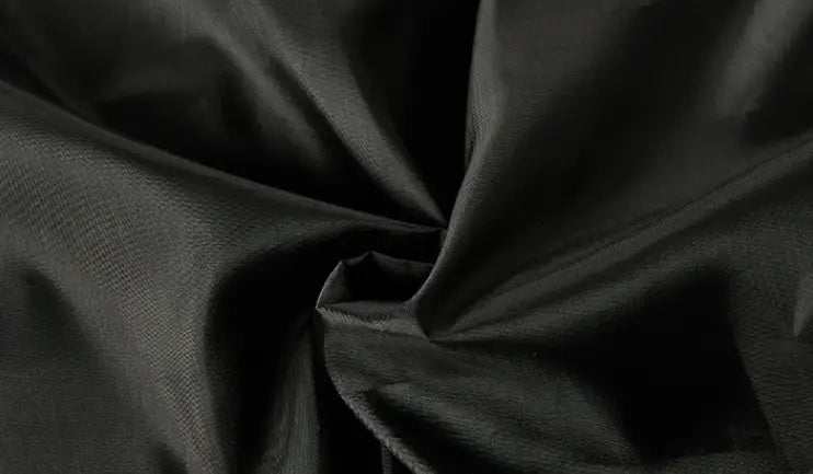 Tela de nailon negra con un brillo sutil y textura de tejido visible en una chaqueta acolchada con capucha para mujer.