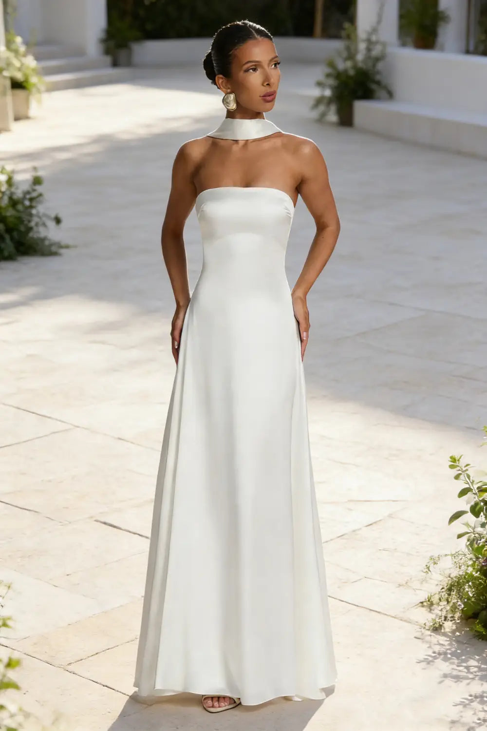 Un elegante vestido de noche sin tirantes de satén blanco, con escote alto drapeado y silueta fluida.