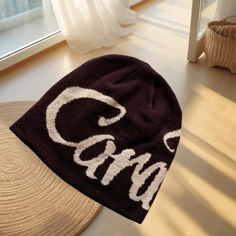 Dark brown knit beanie hat with a prominent white cursive carr embroidered letter logo.