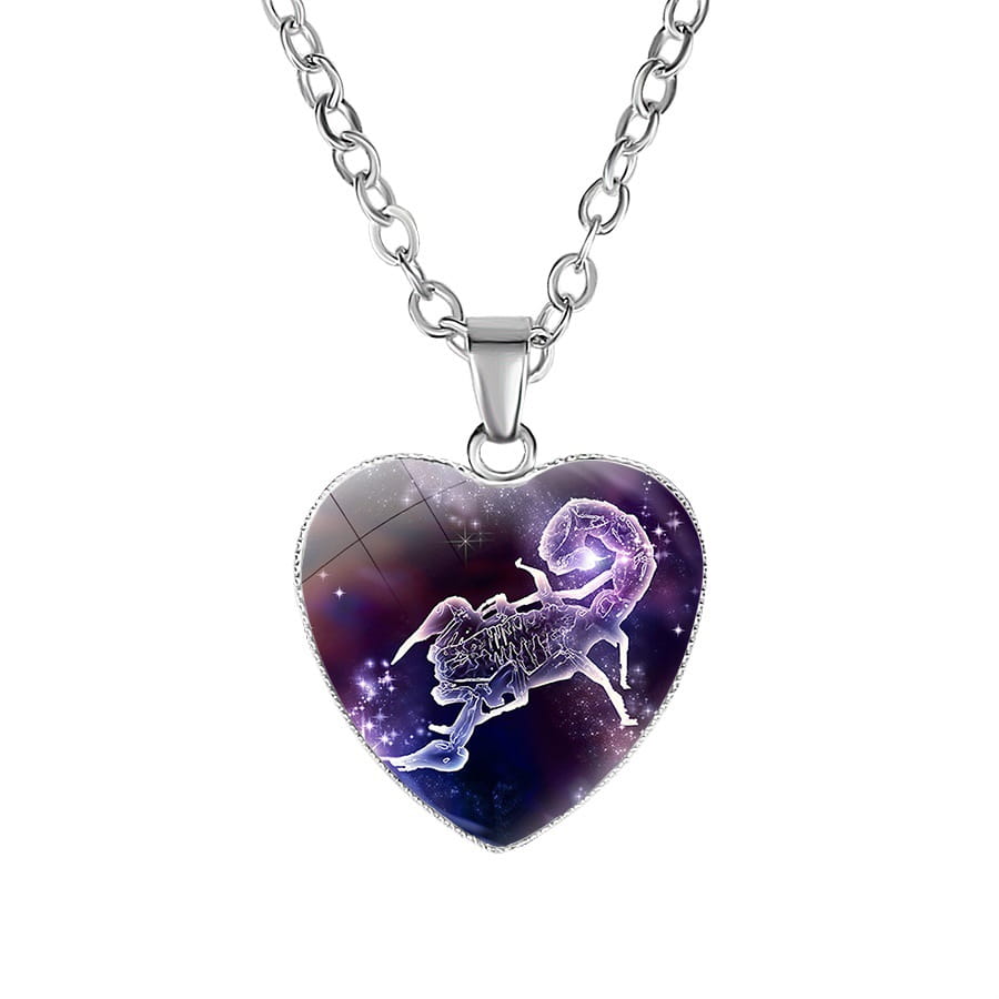 A heart-shaped pendant necklace with a silver-toned chain featuring a glass-covered Scorpio zodiac sign against a purple galaxy background.