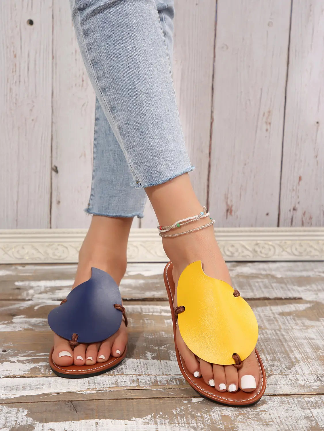 Blue and yellow leaf-shaped leather women’s casual flat flip flop sandals with brown soles.