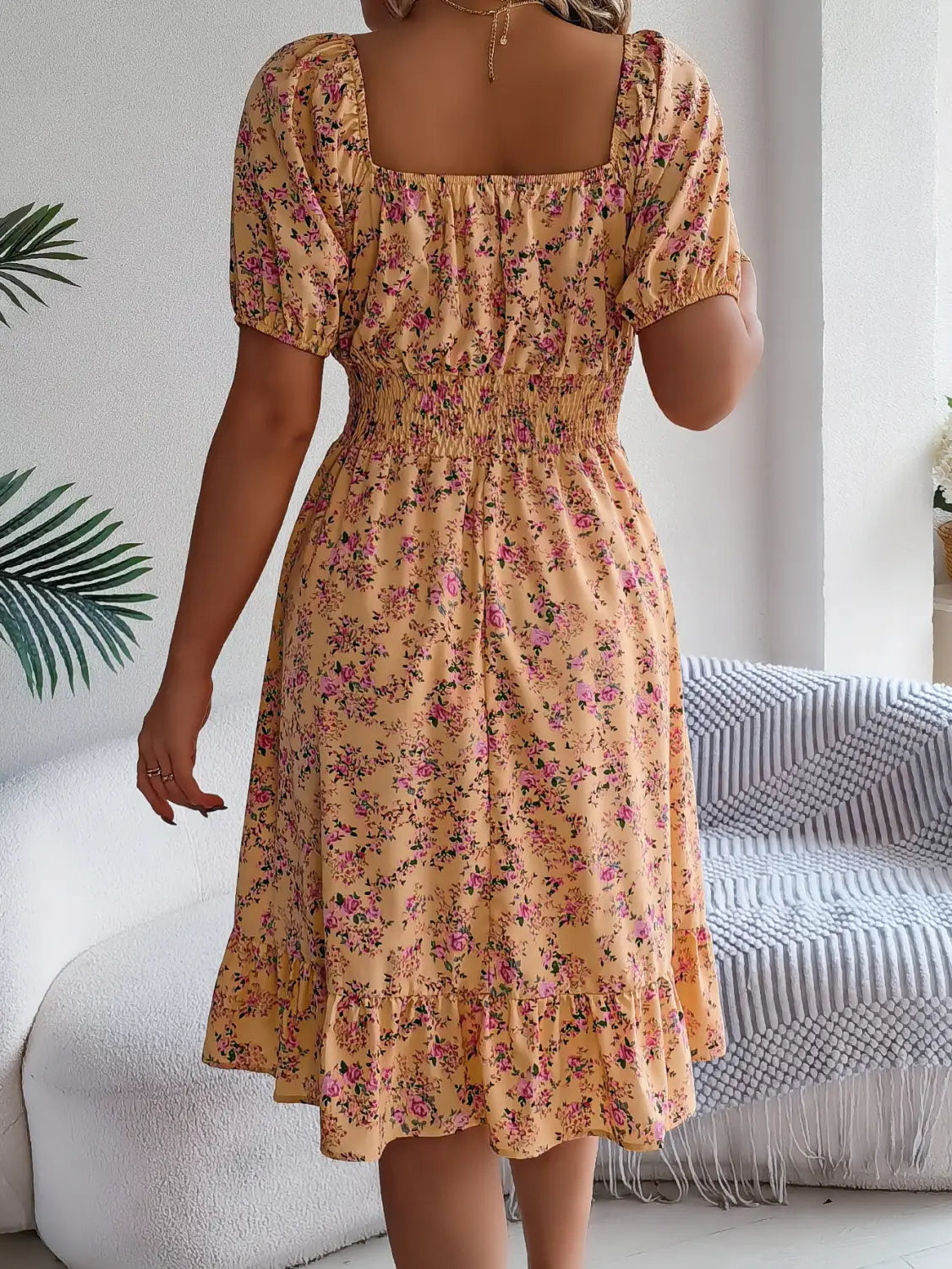 Robe d’été à encolure carrée florale pêche clair, manches bouffantes et volants, avec de délicates fleurs roses sur un tissu léger.