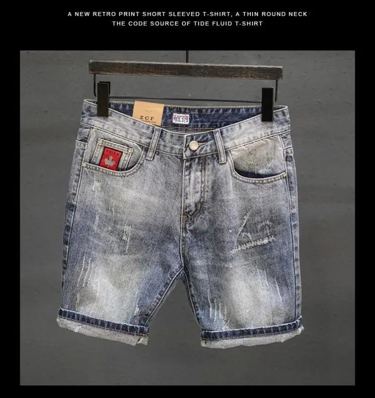 Distressed maple leaf denim shorts featuring light-wash material, frayed hems, and a red patch on the front pocket.