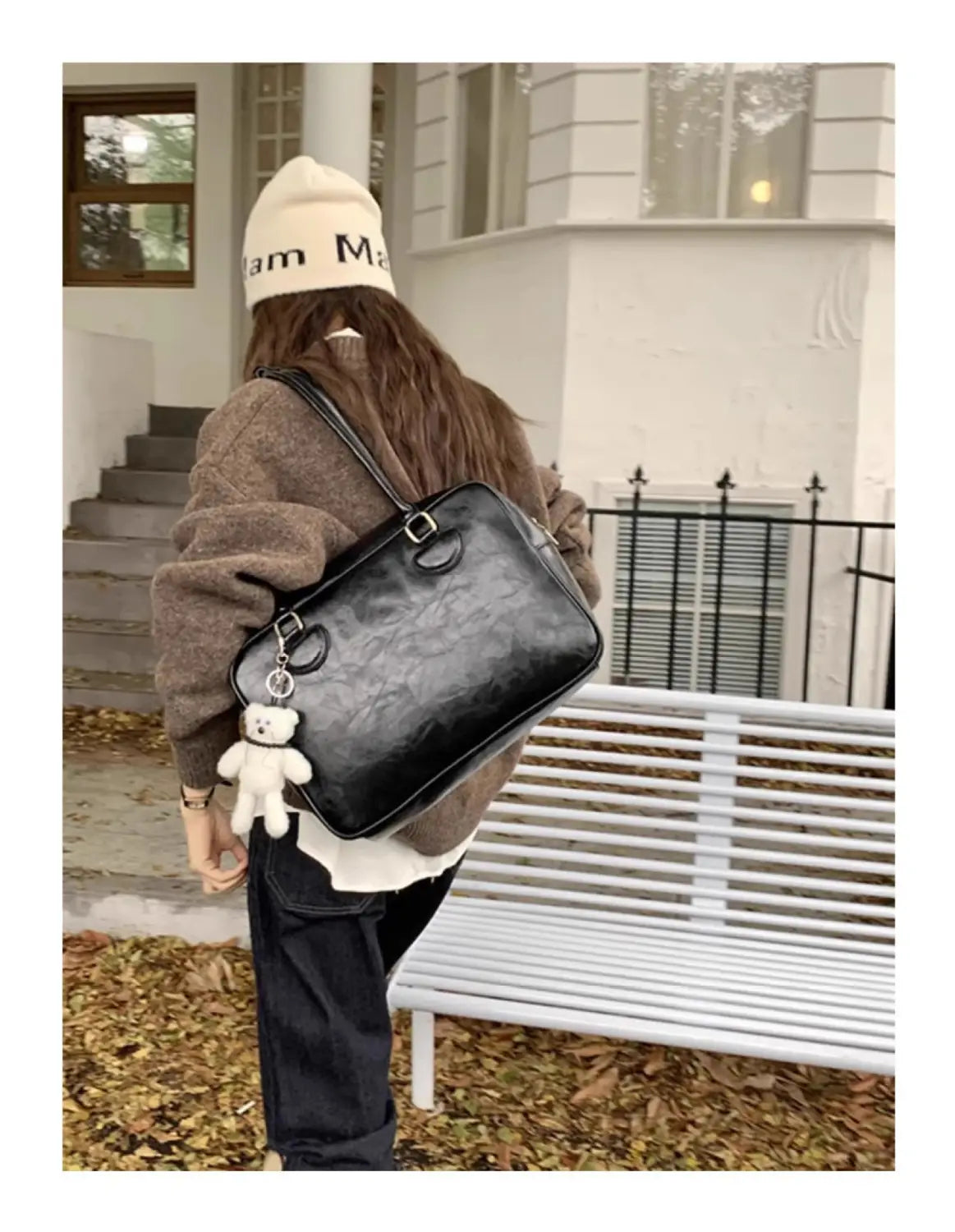 Black textured leather large capacity shoulder bag with white teddy bear charm hanging from the strap.