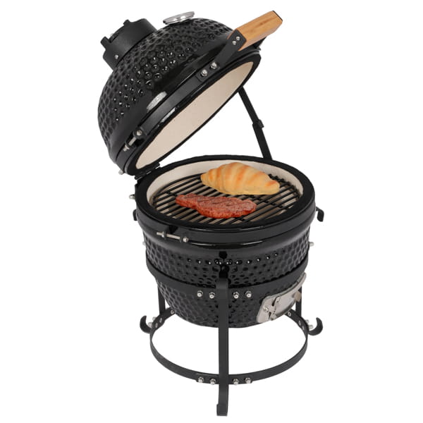 Black ceramic 13 inch kamado charcoal grill with perforated exterior, light interior, and wooden-handled tool resting on the lid.