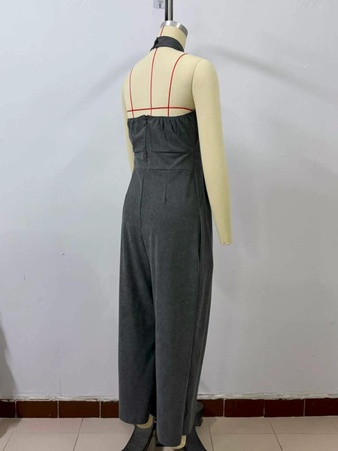 Grauer plissierter Halterneck-Jumpsuit mit weitem Bein, von hinten dargestellt, mit Reißverschluss-Verschluss.