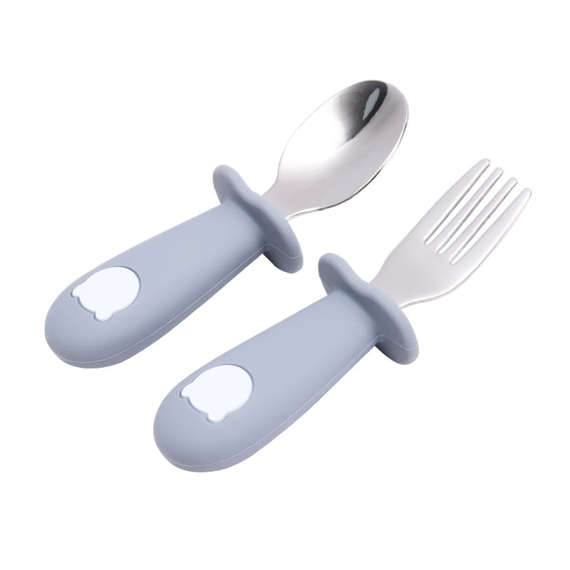 Ensemble cuillère et fourchette pour enfants à manches en silicone gris, avec des têtes en acier inoxydable et des autocollants représentant la tête d’un ours blanc, conçu pour bébé.
