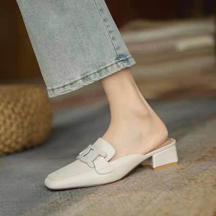 White leather mule shoe with a square toe and block heel featuring a decorative metal buckle strap across the vamp.