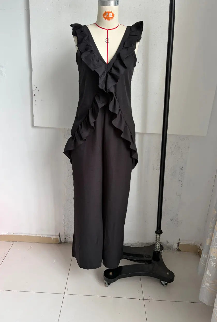 Black ruffled sleeveless jumpsuit with a flowing layered design displayed on a mannequin for resort wear.