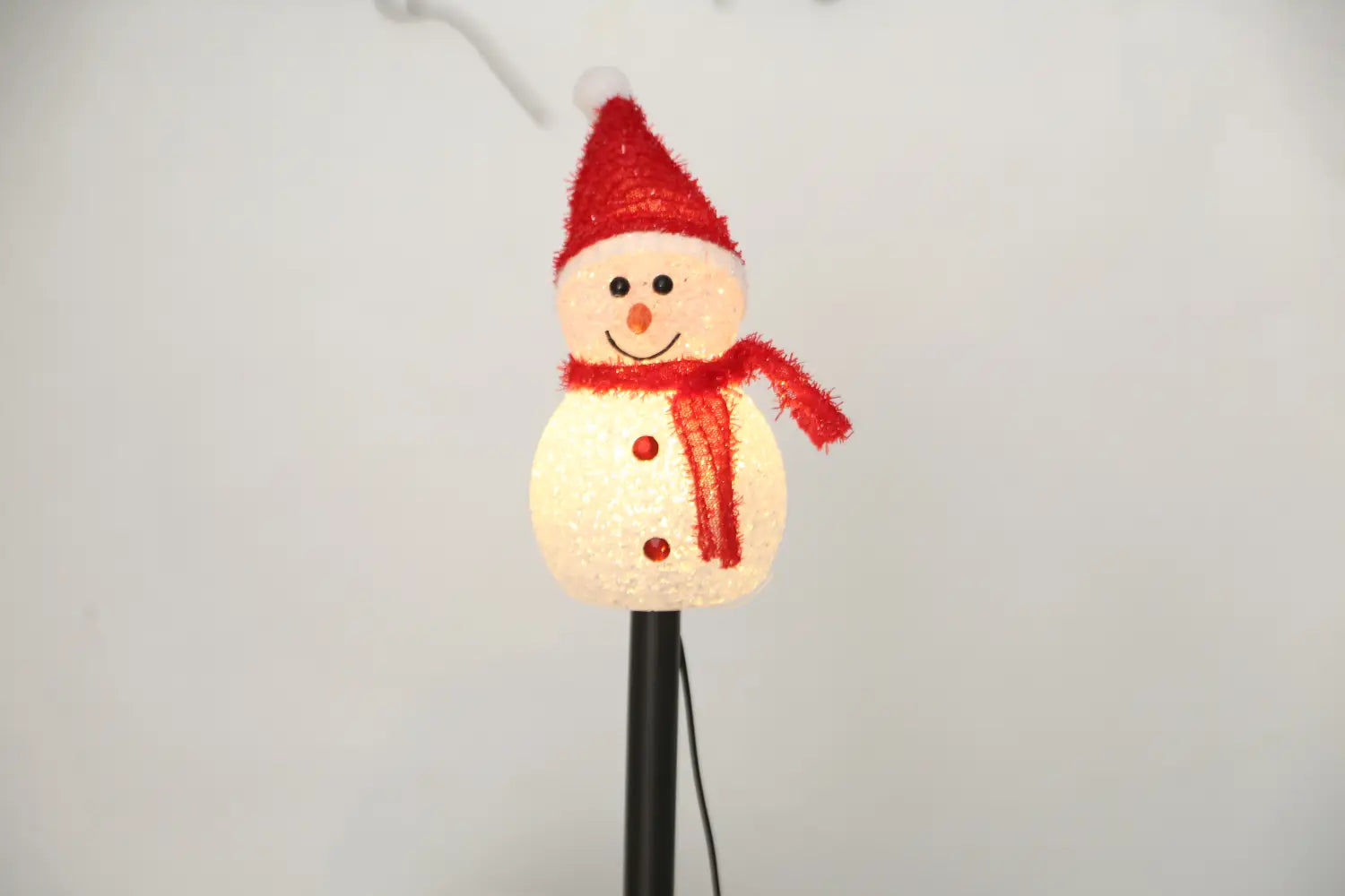Un brise-soleil de jardin de bonhomme de neige solaire blanc lumineux, avec bonnet et écharpe rouges scintillants et trois boutons rouges, conçu pour un usage extérieur, avec une classification d’étanchéité IP55.