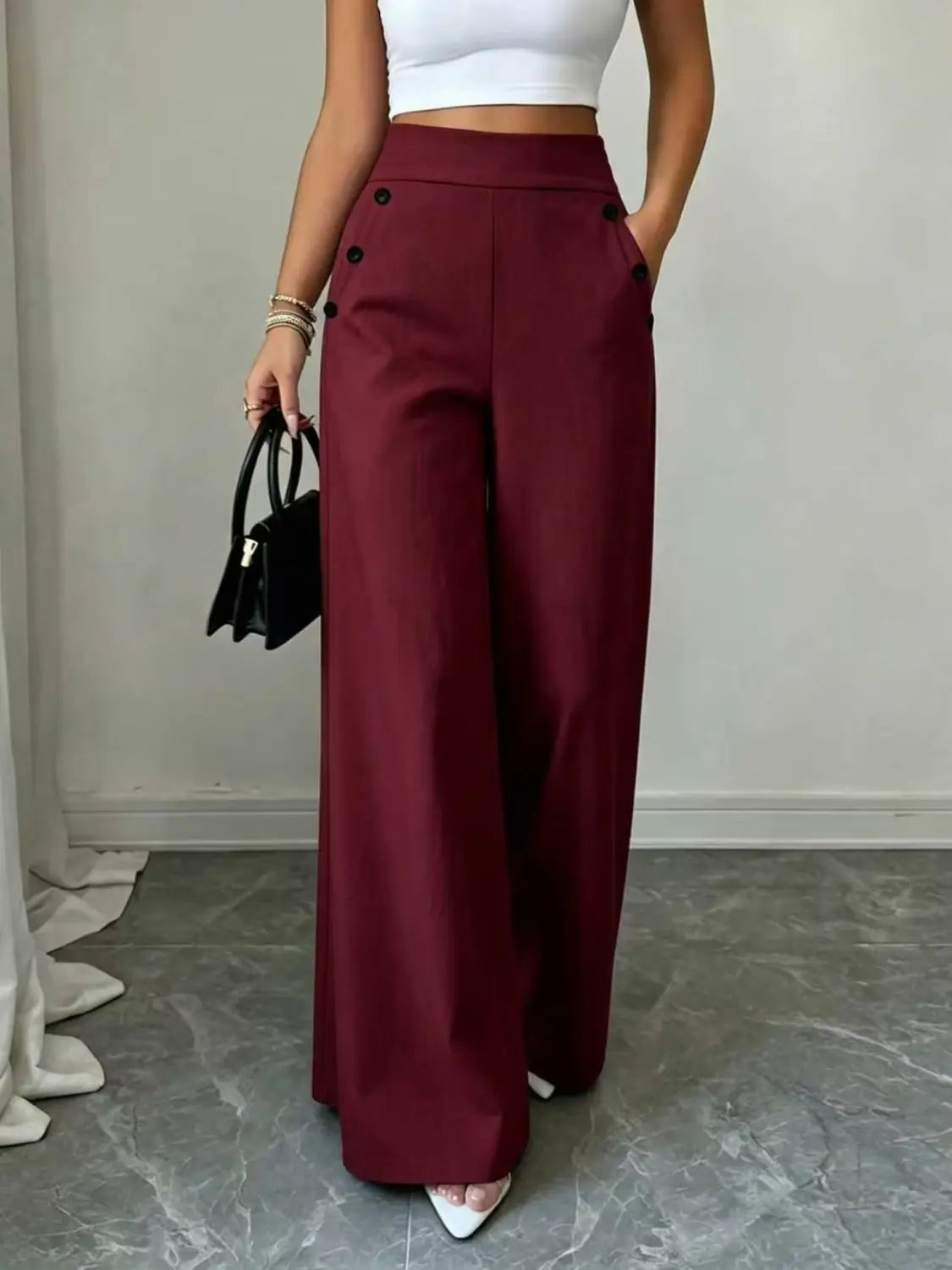 Pantalon ample taille haute bordeaux avec détails de boutons noirs sur les côtés, conçu pour une tenue élégante et confortable.