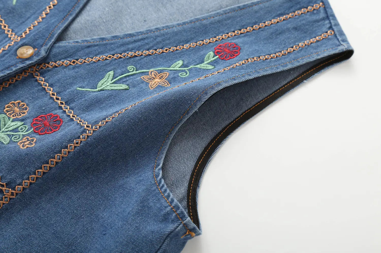 Blaue Jeansweste mit farbenfroher floraler Stickerei in Rot, Grün und Orange, dargestellt in der Kollektion bestickter floraler Jeanswesten.