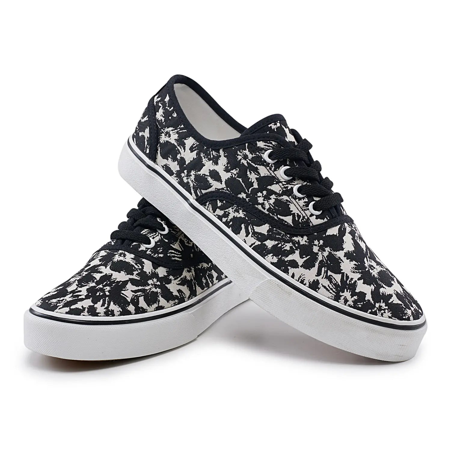 Baskets décontractées basses en toile pour femmes Vans à motif floral noir et blanc, dessus en toile classique, lacets noirs et semelle en caoutchouc blanche.
