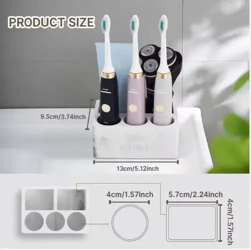 White rectangular ceramic toothpaste holder with three slots holding black pink and white electric toothbrushes for marble bathroom organization.