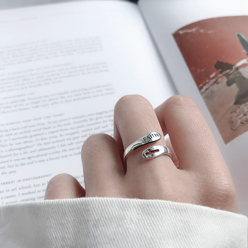A sleek silver faith cross wrap ring with an adjustable band featuring a minimalist open-style design and an engraved faith inscription.