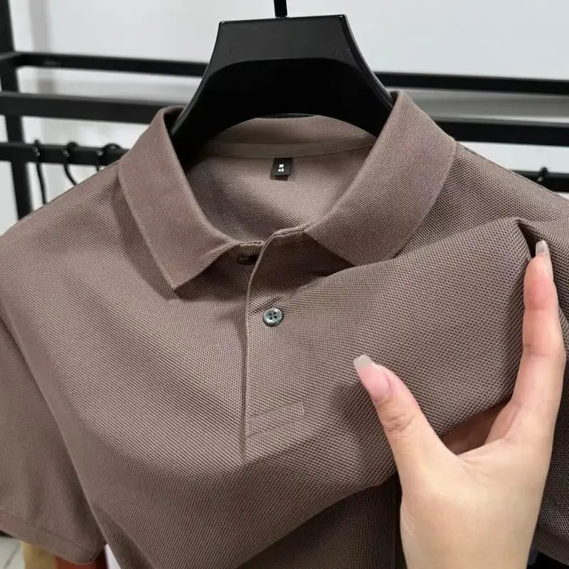 Ein taupefarbenes Herren-Strickpolohemd mit Textur aus Baumwolle mit klassischem Kragen und einfacher Knopfverschluss, als Freizeithemd konzipiert.