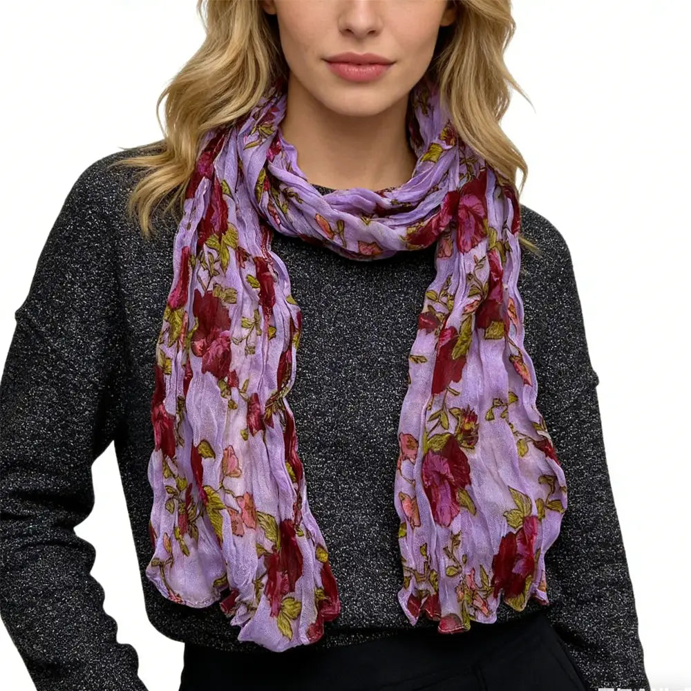 Une écharpe en polyester froissé à fleurs magenta fluide, avec un tissu transparent lavande éclatant et un motif floral de fleurs rouge foncé et vertes.