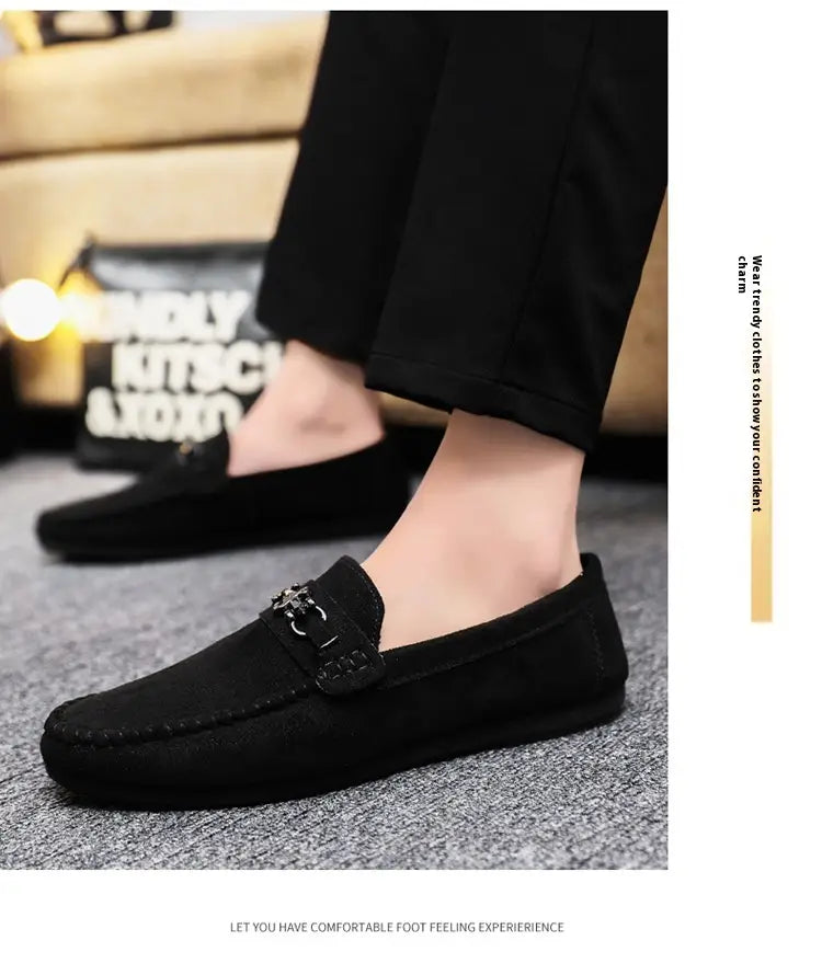 Mocassins à enfiler en daim noir avec un détail de boucle métallique, présentés comme des mocassins à enfiler en daim marron pour homme avec mors de cheval.
