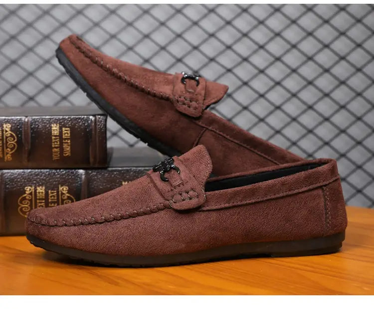 Mocassins à enfiler en daim marron pour homme avec mors de cheval, comportant un détail de boucle métallique noire.