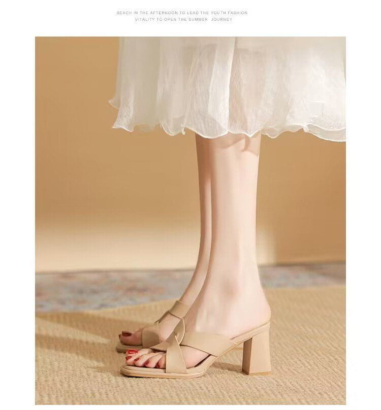 Beige leather chunky heel open toe mule sandals with a crisscross strap design.