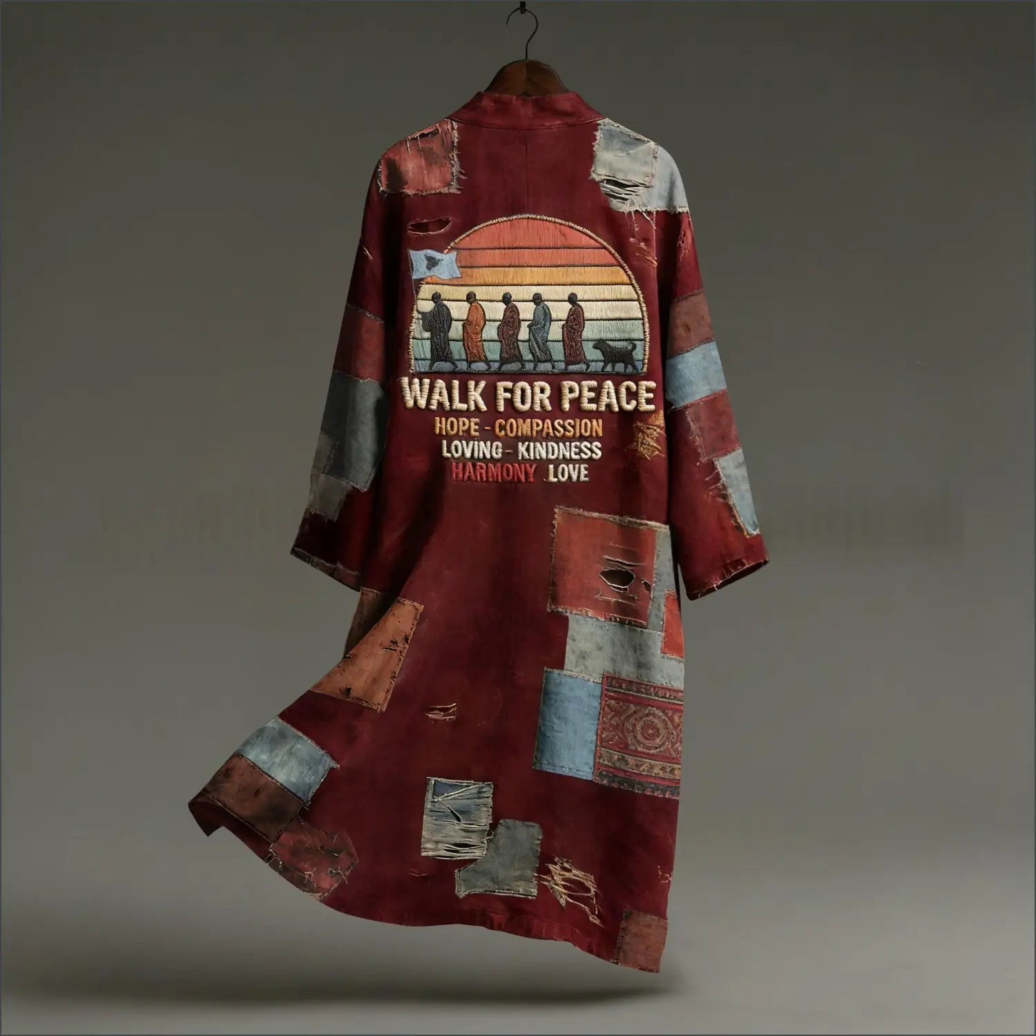 Ein bordeauxfarbenes Vintage-Blumenmuster-Midikleid mit langen Ärmeln, das ein Patchwork-Kimono-Design zeigt, mit verwitterten Stoffapplikationen in gedämpften Blau-, Grau- und Erdtönen sowie einer Vintage-Sonnenuntergangsgrafik mit inspirierendem Text.
