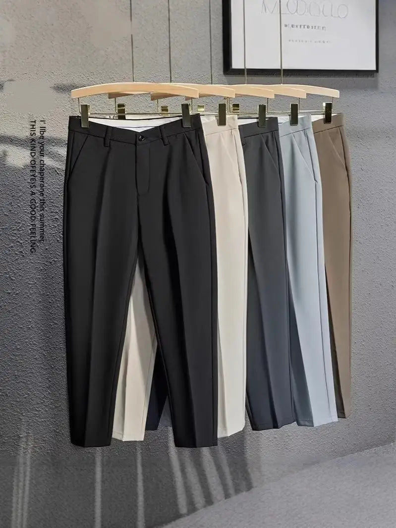 Herren-Slim-Fit-Anzughose aus schwarzem, cremefarbenem Grau und beigen Tönen, präsentiert auf hölzernen Bügeln vor einer strukturierten Wand