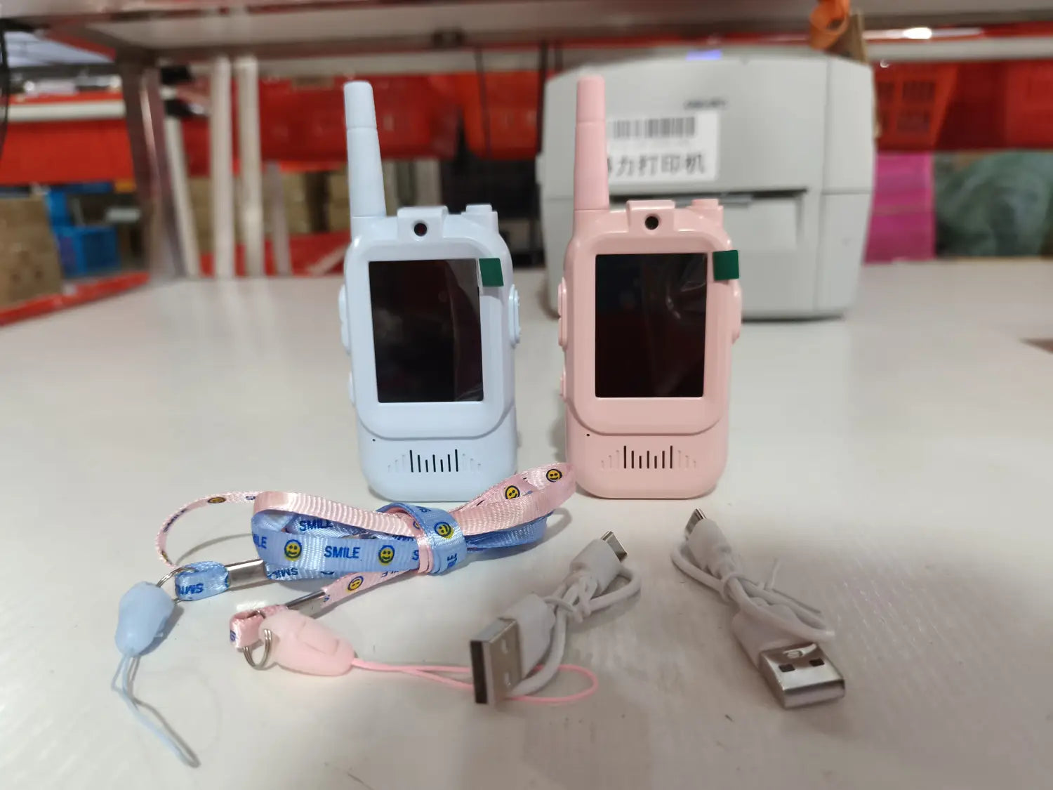 two rechargeable kids video walkie talkies in light blue and pink with small antennas, screens, and speaker grilles for child communication.